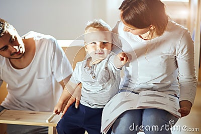 Family reading instruction and assemble furniture together at living room of new apartment pile of moving boxes on Stock Photo