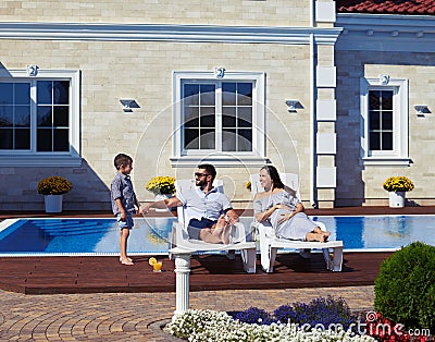 Family relaxing in front of modern house with pool Stock Photo