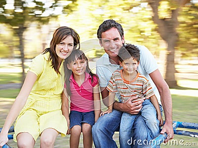 Family Riding On Roundabout In Park Stock Photo