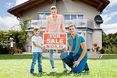 Family With A Sale Sign Outside Their Home Stock Photo