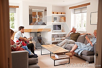 Family With Senior Parents And Adult Offspring Relaxing In Lounge At Home Together Stock Photo