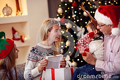 Family sharing gift on Christmas- smiling mother giving present Stock Photo