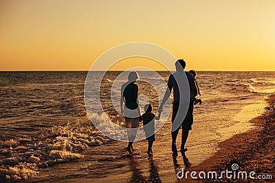 Family silhouettes on beach at sunset Stock Photo