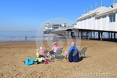 Family sitting on beach by pier Editorial Stock Photo