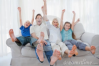 Family sitting on a couch and raising arms Stock Photo