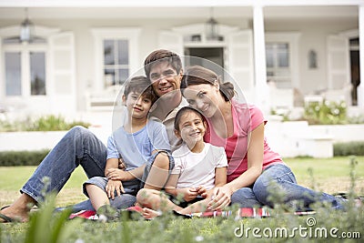Family Sitting Outside House On Lawn Stock Photo