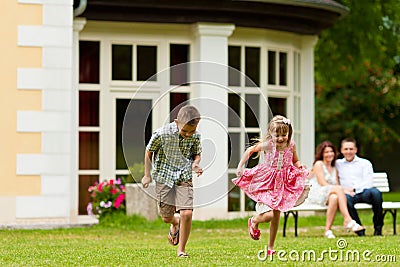 Family sitting and playing in front of their home Stock Photo