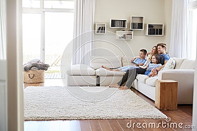 Family Sitting On Sofa At Home Watching TV Together Stock Photo