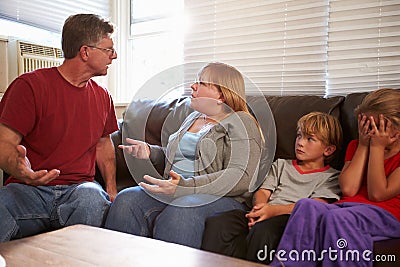 Family Sitting On Sofa With Parents Arguing Stock Photo