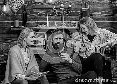 Family spending lovely evening in countryside. Woman reading book while her husband and daughter drink tea. Handsome Stock Photo