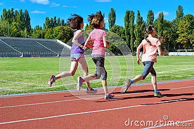 Family sport and fitness, happy mother and kids running on stadium track outdoors, children healthy lifestyle concept Stock Photo