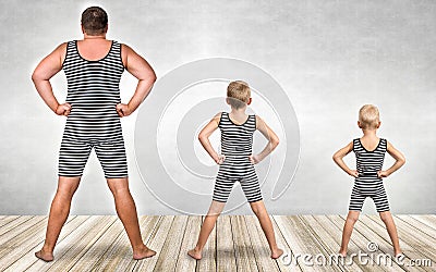 Family of strongman. The father of two sons in vintage costume of athletes perform strength exercises. Family look. Stock Photo