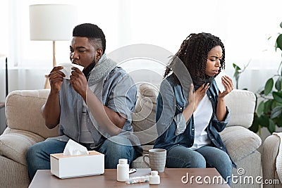 Family Suffering From Coronavirus At Home. Sick Black Couple Coughing On Couch Stock Photo