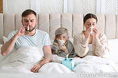 Family suffering from runny nose in bed at home Stock Photo