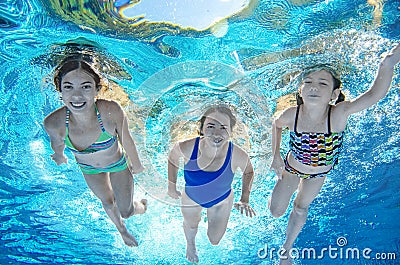 Family swims in pool underwater, happy active mother and children have fun under water, fitness and sport with kids Stock Photo