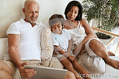 Family With Tablet Portrait. Interracial Parents Using Portable Digital Device Together. Stock Photo