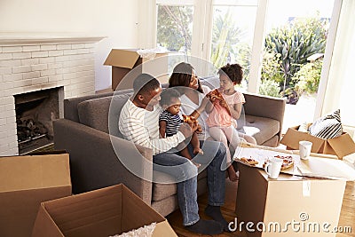 Family Take A Break On Sofa With Pizza On Moving Day Stock Photo