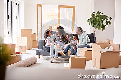 Family Taking A Break And Sitting On Sofa Celebrating Moving Into New Home Together Stock Photo