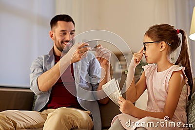 Father photographing daughter by cellphone at home Stock Photo
