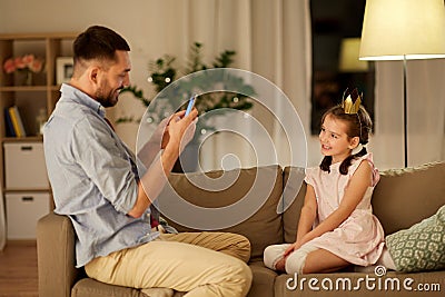 Father photographing daughter by cellphone at home Stock Photo