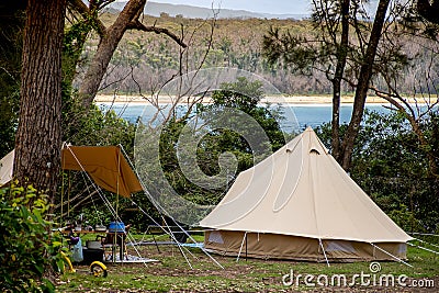 Family tent setup at the campsite surrounding by bush forest near the ocean bay in Australia. Family vacation travel camping Stock Photo