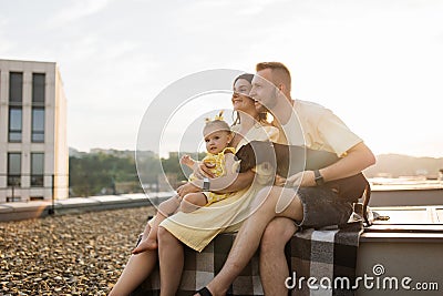 Family of three with dog sitting on blanket on open space Stock Photo