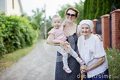 Family of three generations outdoors: senior woman, her adult granddaughter and toddler great granddaughter Stock Photo