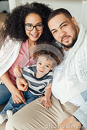 Family of three looking at camera. Mother father and son sitting Stock Photo