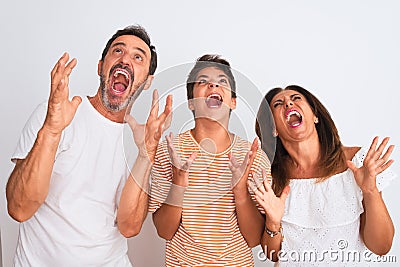 Family of three, mother, father and son standing over white isolated background crazy and mad shouting and yelling with aggressive Editorial Stock Photo