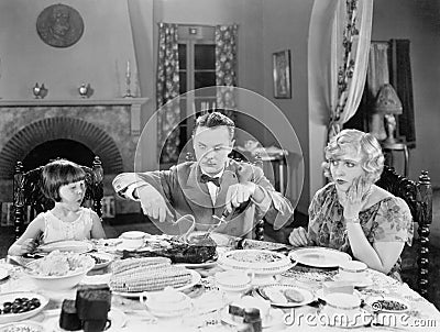Family of three sitting together having dinner Stock Photo