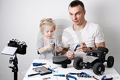 Family time: Dad and daughter repair the rc radio controlled buggy car model and lead a video blog. Stock Photo