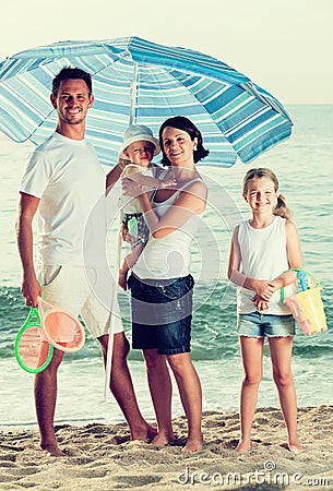 Family under sun umbrella on the beach Stock Photo