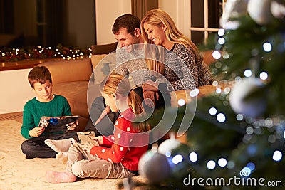 Family Unwrapping Gifts By Christmas Tree Stock Photo