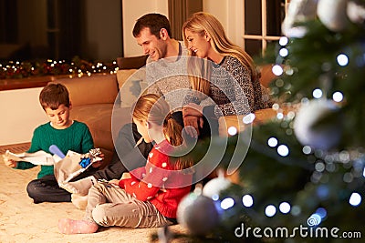 Family Unwrapping Gifts By Christmas Tree Stock Photo