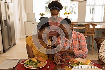 Family using mobile phone on dining table at home Stock Photo