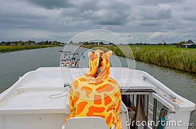 Family vacation, summer holiday travel on barge boat in canal, man in funny kigurumi by steering wheel on river cruise trip Stock Photo