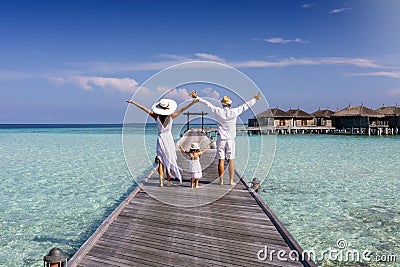 A family on vacation walks along a wooden pier in the Maldives Stock Photo