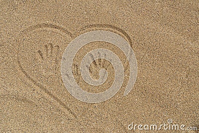 Mom`s, Dad`s and child`s handprints trace on the sand in heart. Stock Photo
