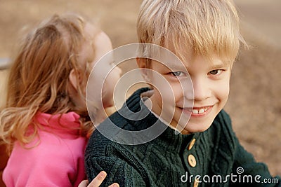 Family on a walk. Brother and beauty cute baby sister playing on the playground. The cute boy smiles Stock Photo