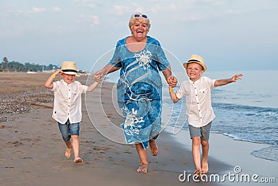 Family walking on the evening beach during sunset.Grandmother and two grandsons. Stock Photo