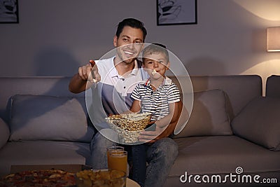 Family watching TV with popcorn in room at time Stock Photo