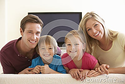 Family Watching Widescreen TV At Home Stock Photo