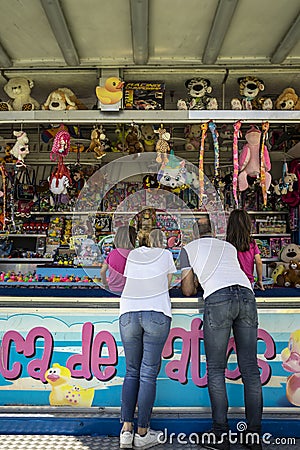 Family with 2 young girls playing at a hook a duck stand Editorial Stock Photo