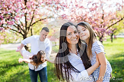 Young parents with small daugthers standing outside in spring nature. Stock Photo