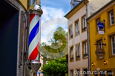 The famous and classic symbol of a barber shop. Close up of rotating red, white and blue barber shop light in Luxembourg, Europe Stock Photo