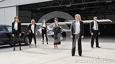 Famous female celebrity with bodyguards surrounded. VIP security agents Stock Photo