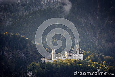 The famous Neuschwanstein Castle in the background of snowy mountains and trees with yellow and green leaves. Bavaria, Germany. Stock Photo