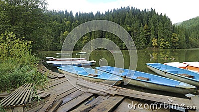 Famous Red Lake with colorful boats near the broken dock in Lack Rosu, Romania Stock Photo