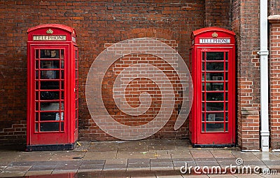 Famous red telephone boxes in London near red brick wall and drain pipe Stock Photo