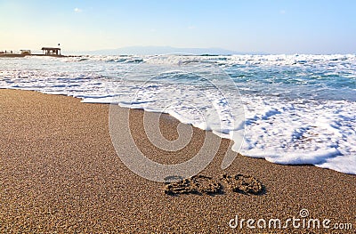 Famous resort of Crete island, Greece. Sand beach seascape with the rays of the sun. 2019 writing on the surface. Beautiful sea Stock Photo